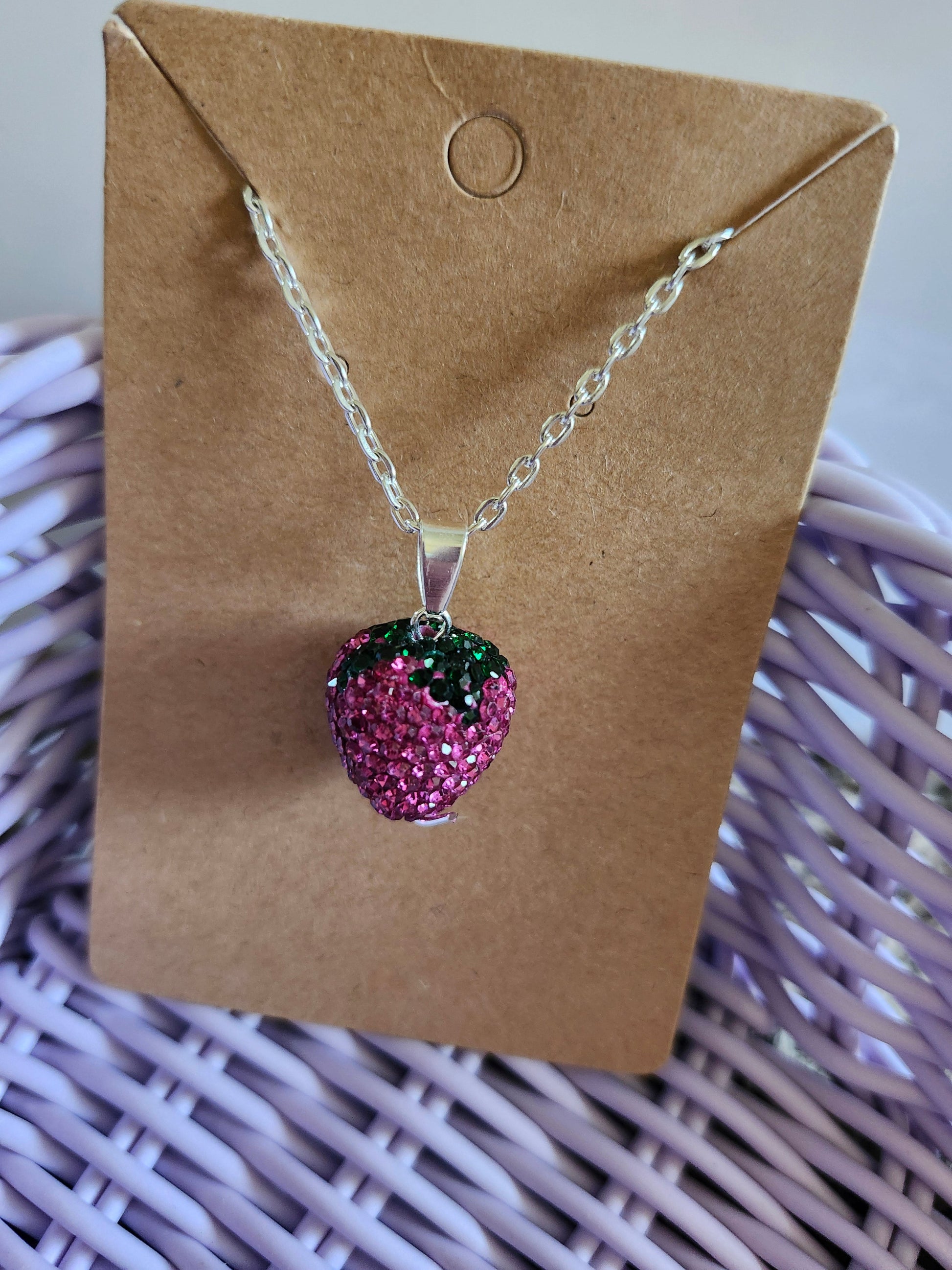 Bling strawberry pendant on a silver chain displayed on a brown card for a stylish accessory