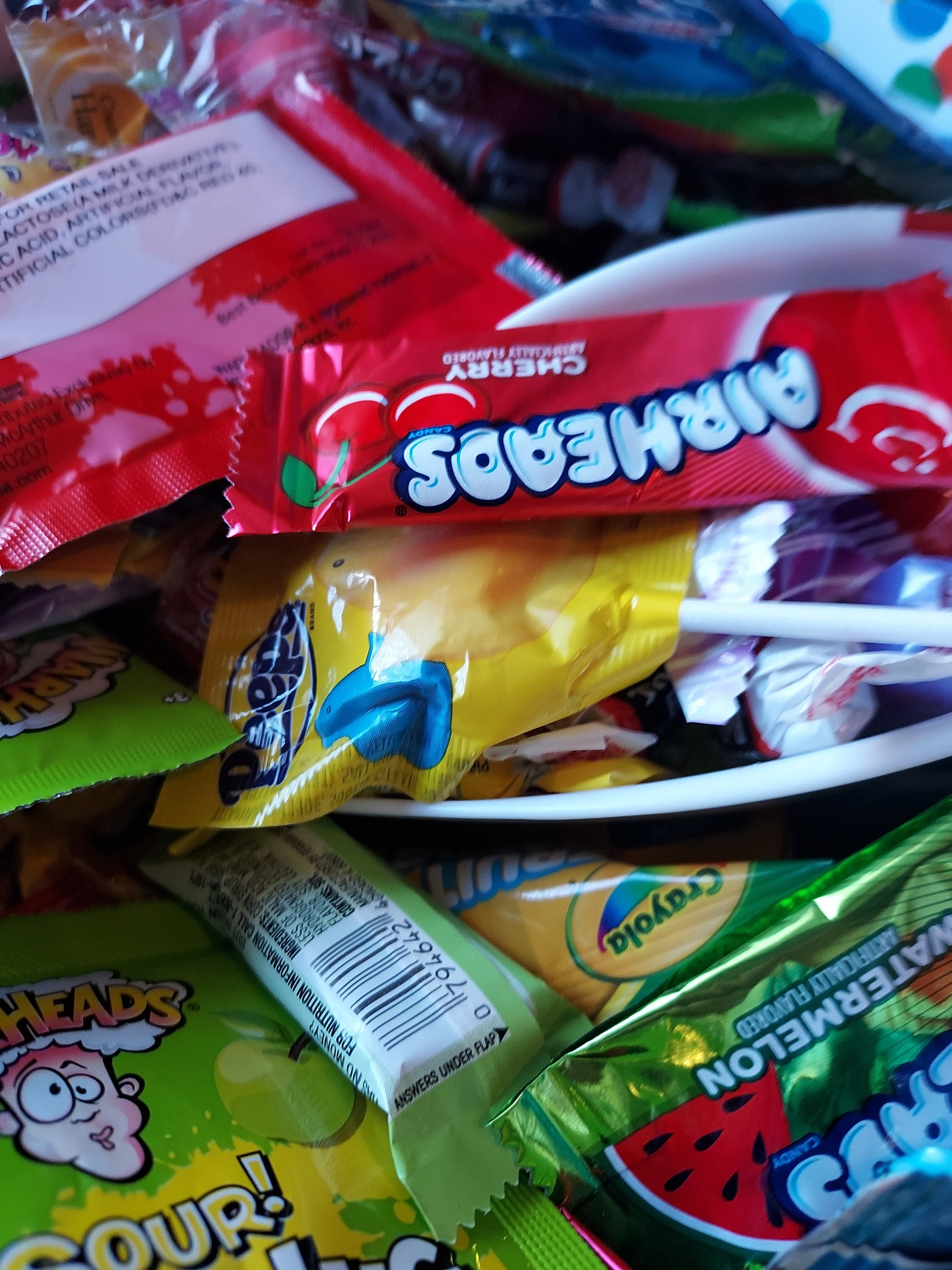 Colorful assortment of candies in a bowl, including Candy Mystery Scoops and various wrappers
