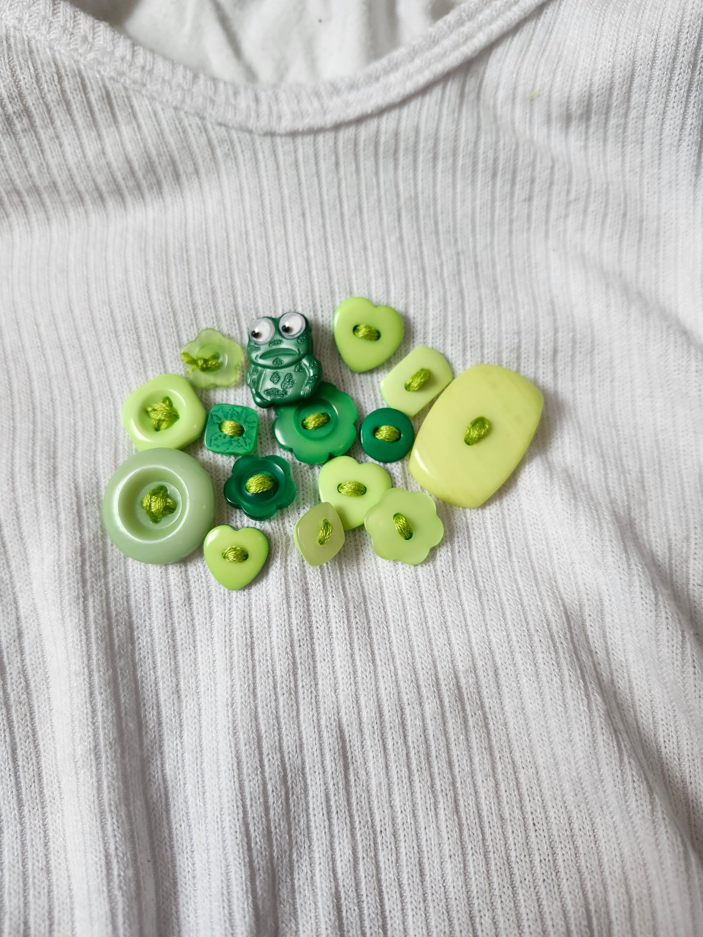 Close-up of handsewn embroidered frog shirt featuring green buttons and frog design