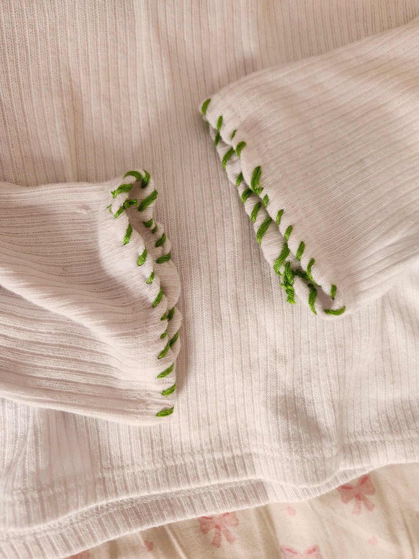 Detail of handsewn embroidered frog shirt showcasing green stitching on the sleeves