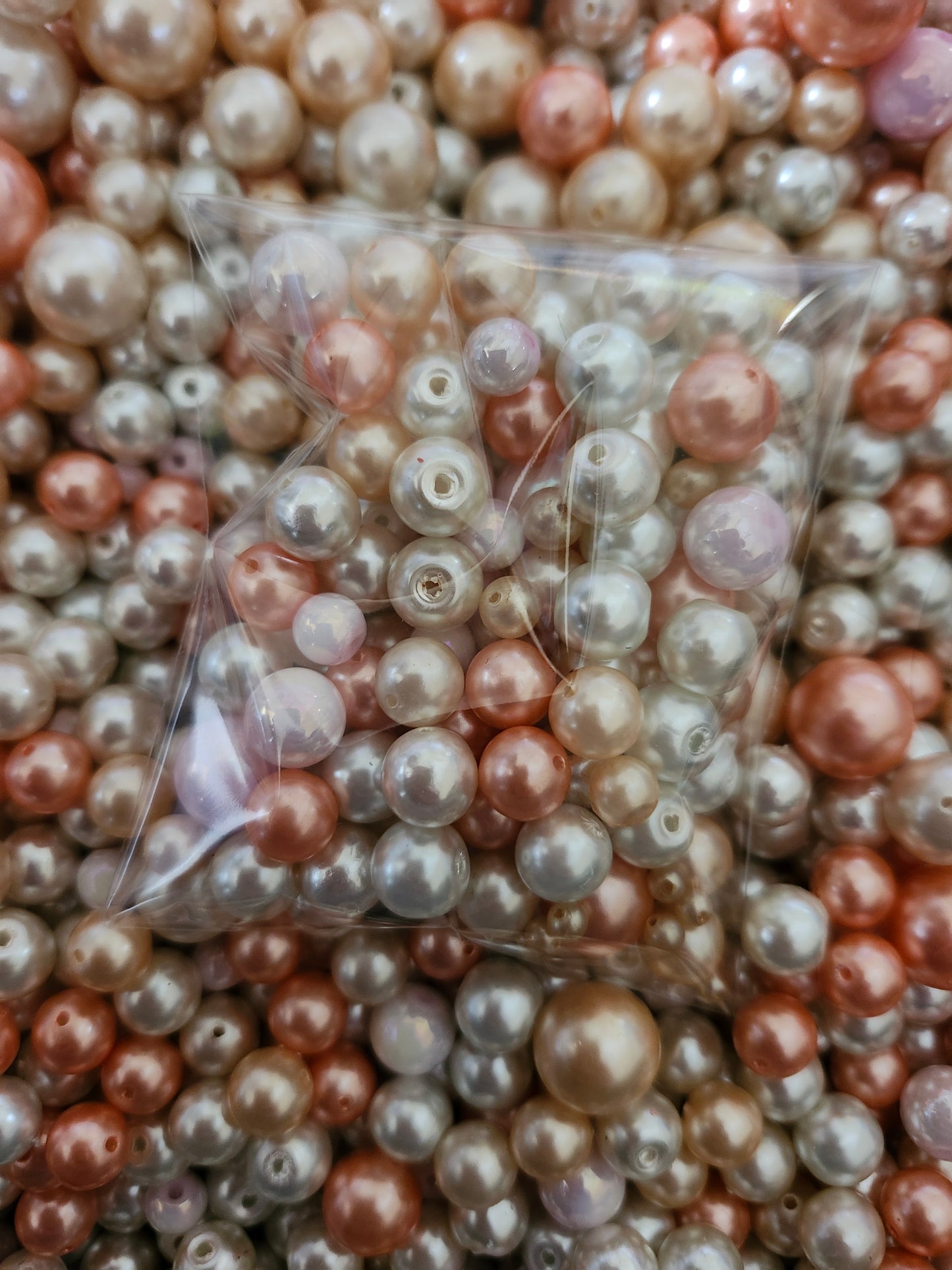 Plastic bag of pink white pearls jewelry making beads on a background of assorted pearls