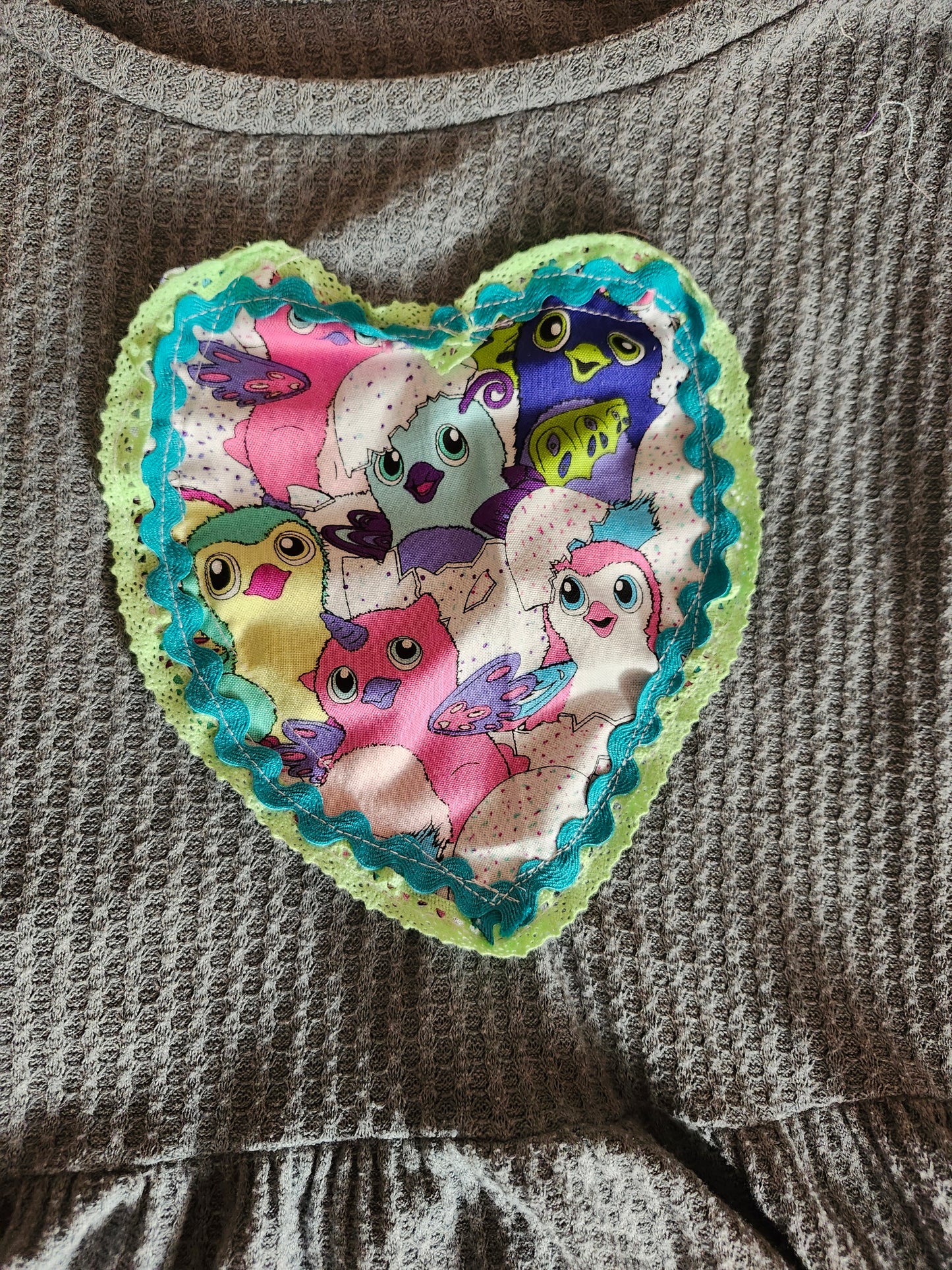 Heart-shaped patch featuring colorful Furbys on a gray fabric dress showcasing upcycled Furby fashion