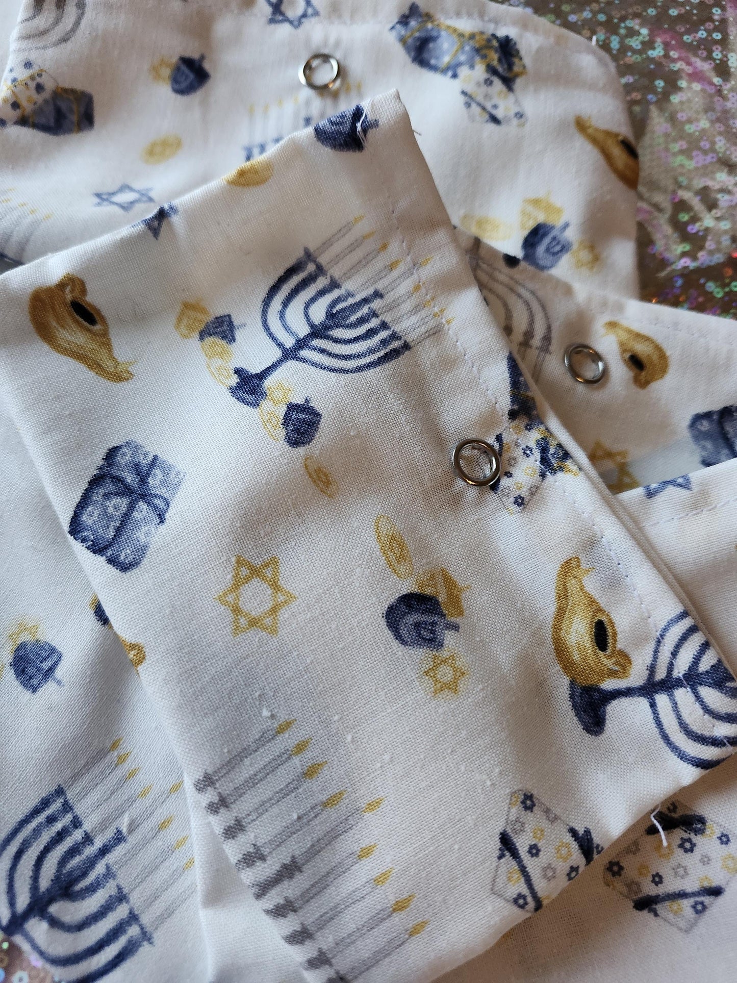 White Hanukkah gift pouch featuring festive patterns of menorahs and dreidels for holiday celebrations