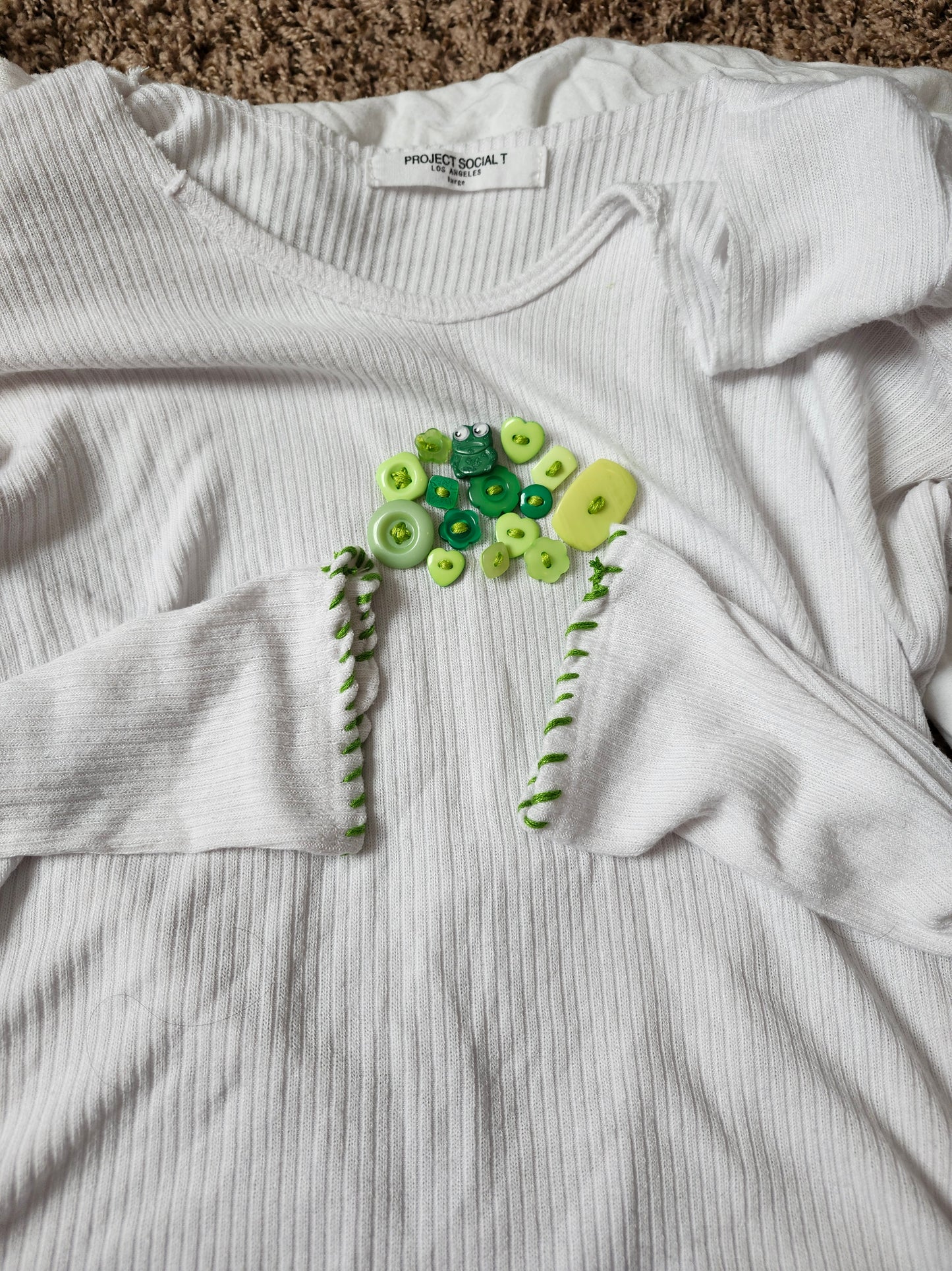 White long-sleeve shirt featuring handsewn embroidered frog shirt design with colorful buttons