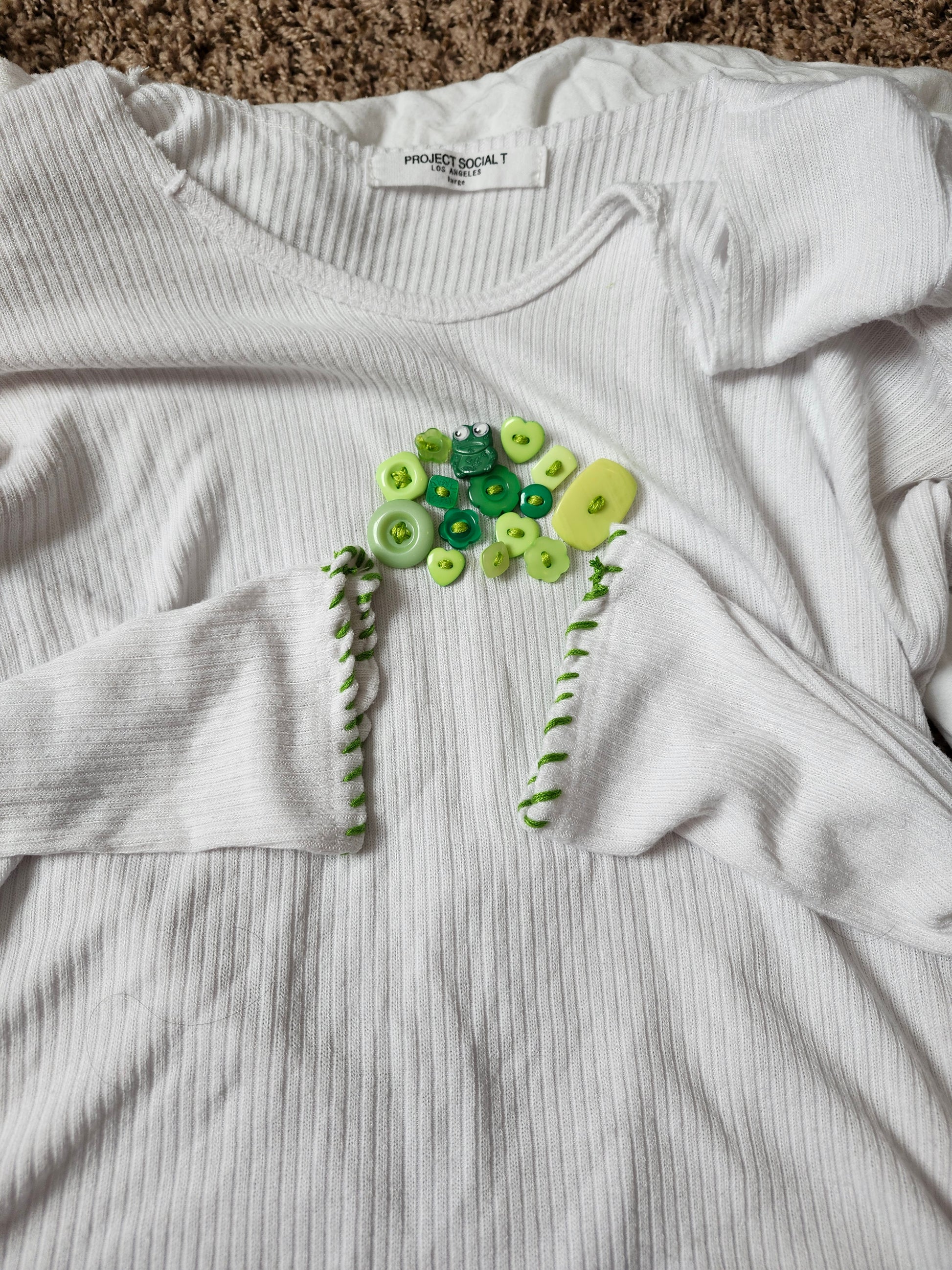 White long-sleeve shirt featuring handsewn embroidered frog shirt design with colorful buttons