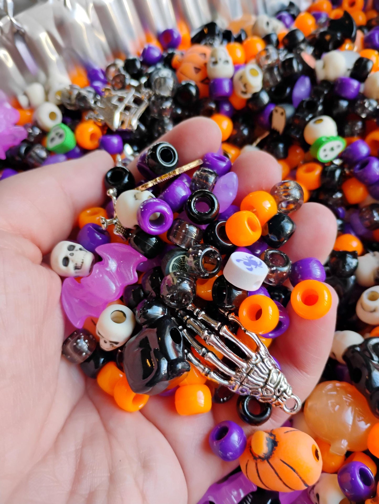 Hand holding assorted Kandi beads Halloween in vibrant colors with skull and skeleton charms