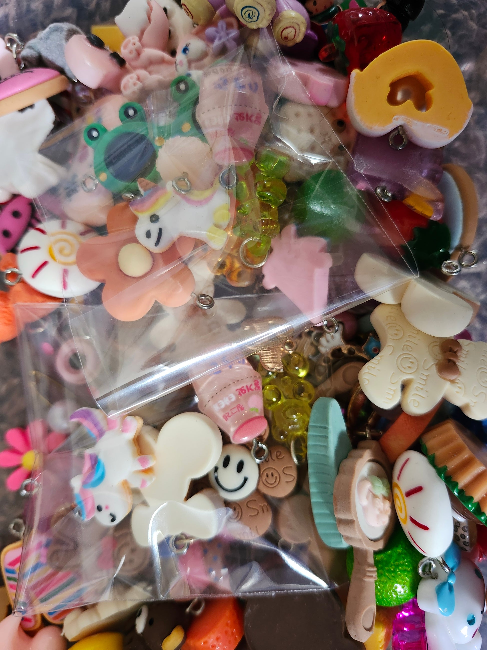 Colorful assortment of kawaii jewelry charms in two plastic bags for creative crafting projects