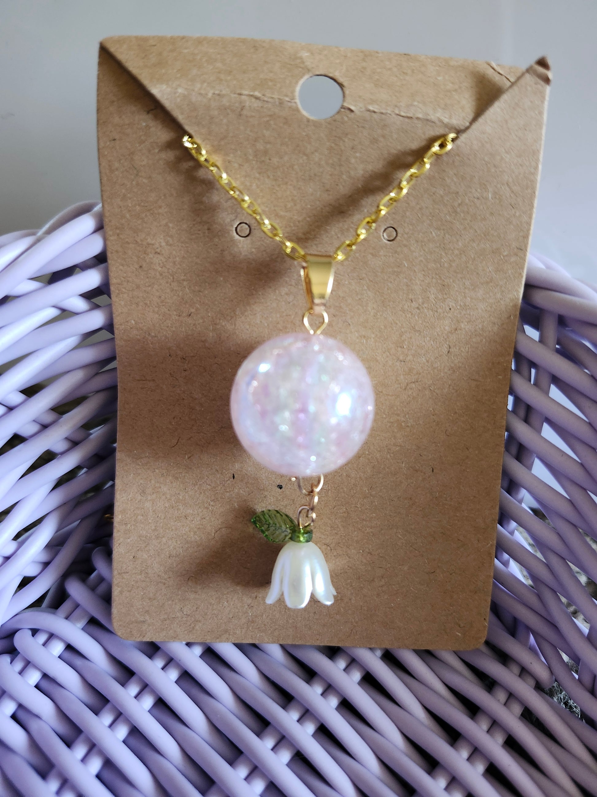 Kawaii pink lily necklace with a shimmering pink bead and a delicate lily charm on a gold chain