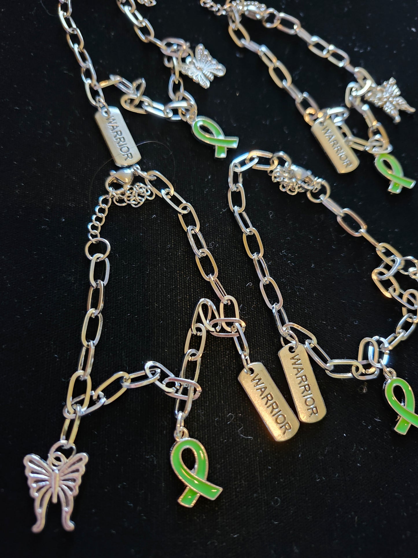 Silver mental health charm bracelet with green ribbon and butterfly charms for support and awareness