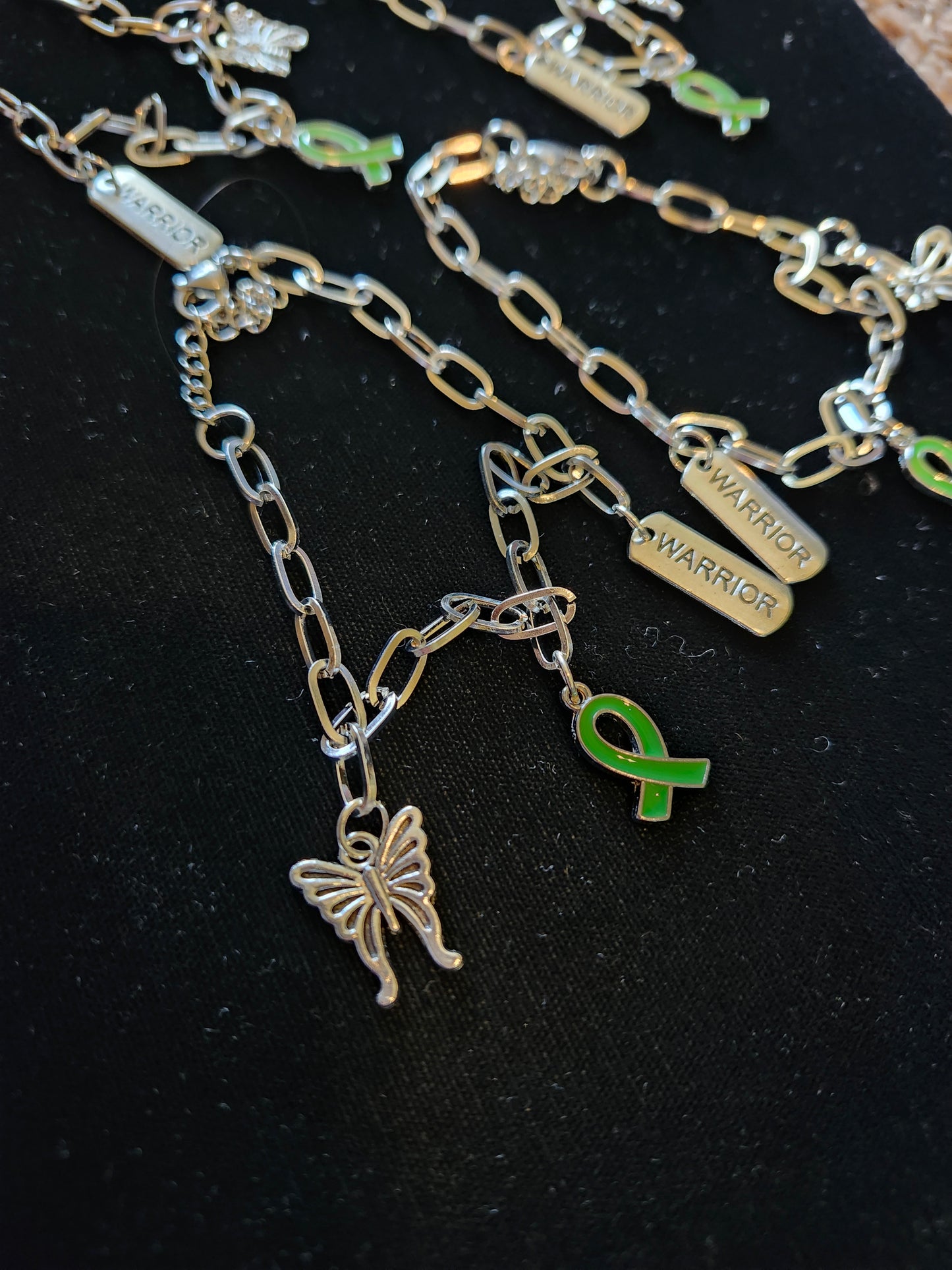Silver mental health charm bracelet featuring butterfly and green ribbon charms for support and awareness