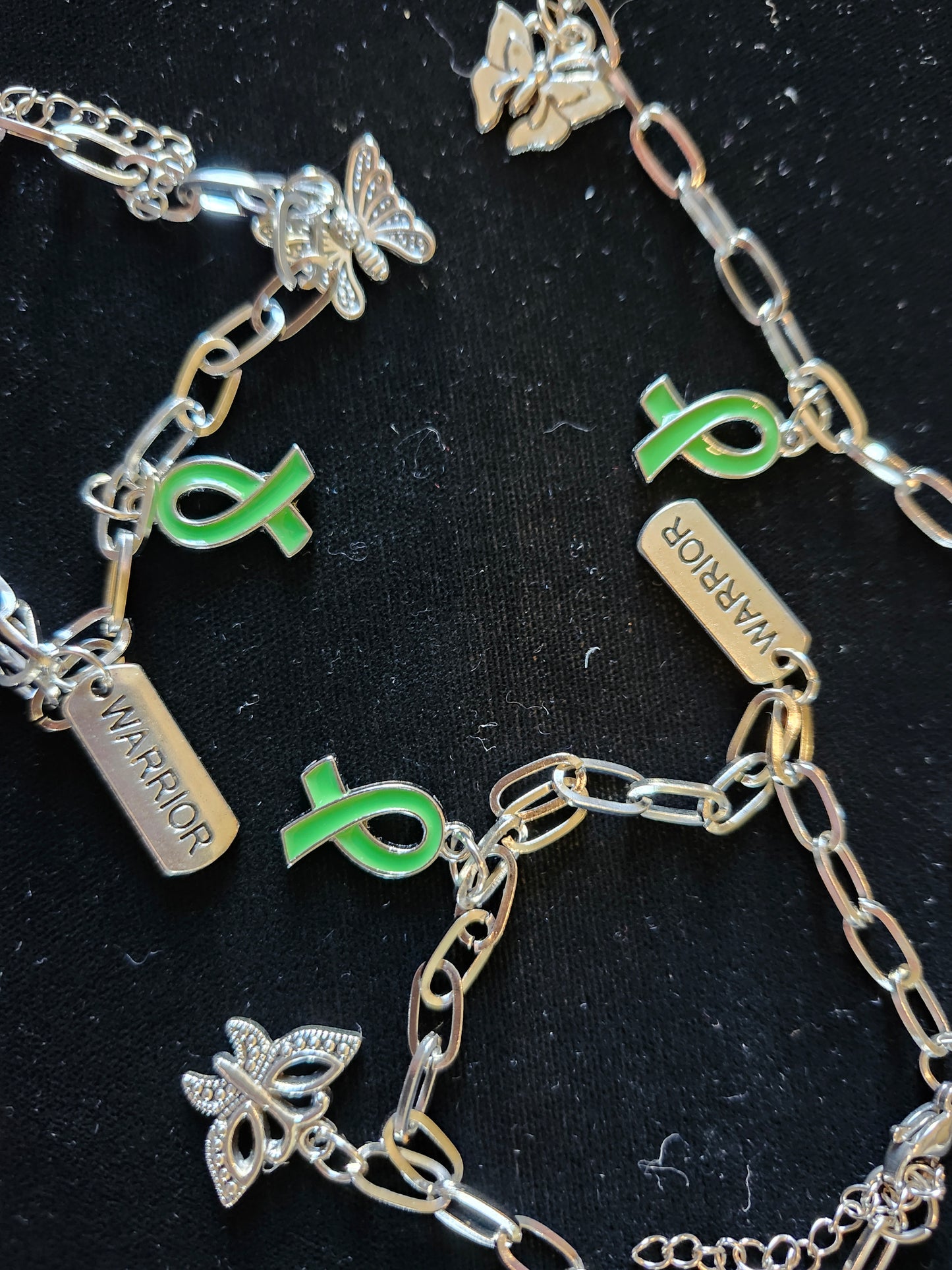 Mental health charm bracelet featuring green ribbons and butterfly charms for support and awareness