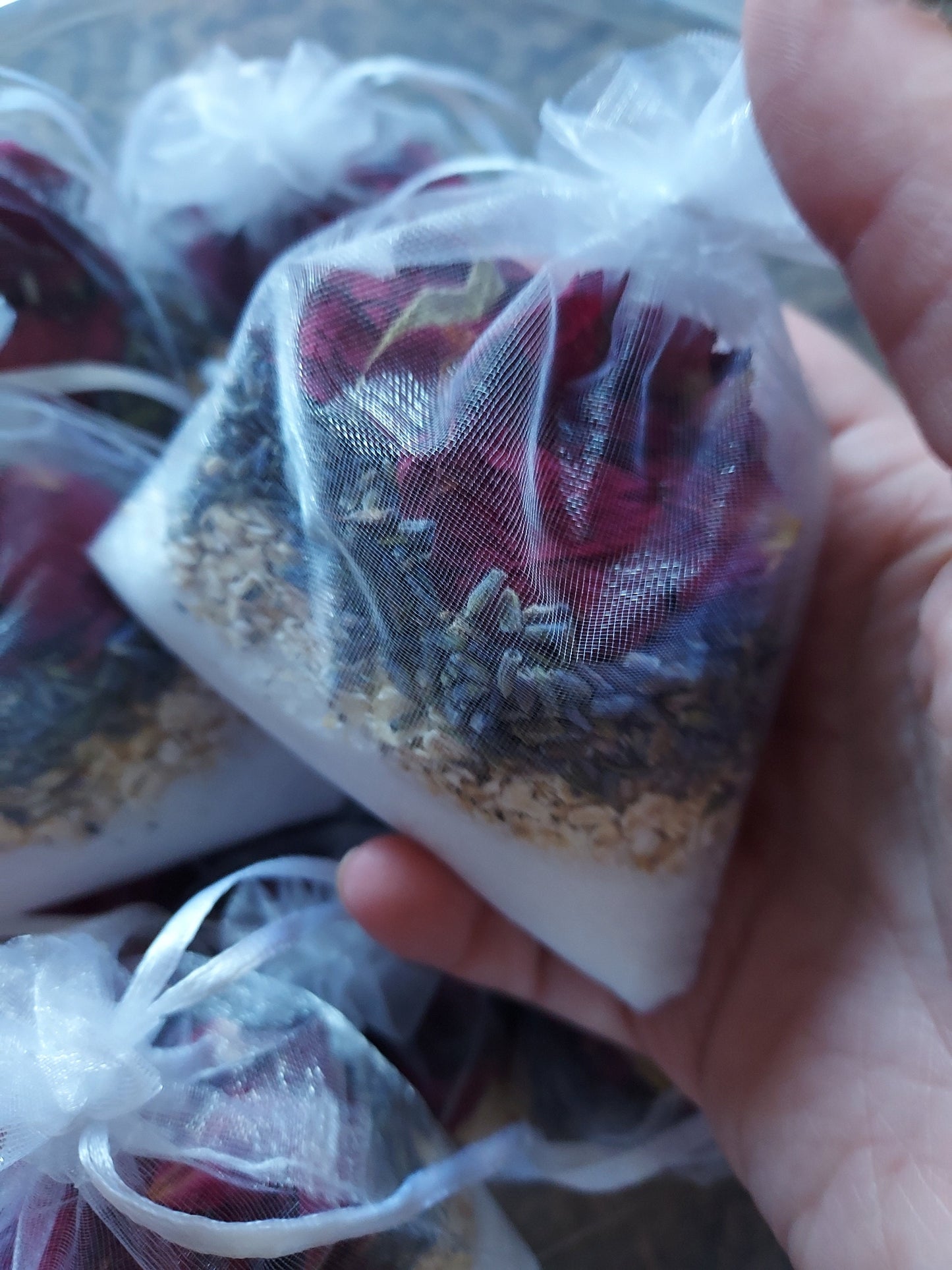 Handheld natural spa bath blend in a sheer pouch with dried flowers and herbs for a relaxing bath experience