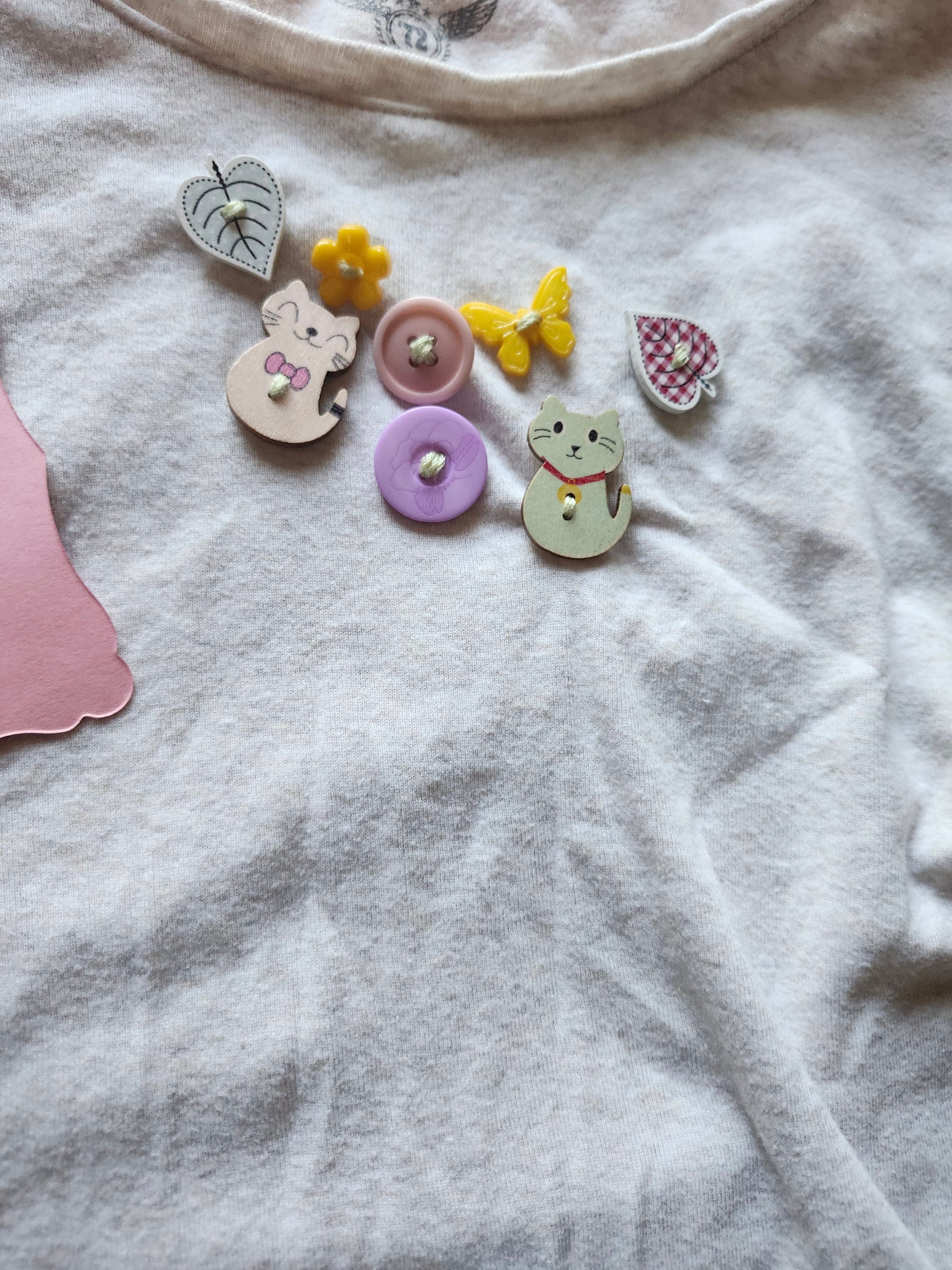 Colorful quirky button designs featuring animals and flowers on a white fabric background