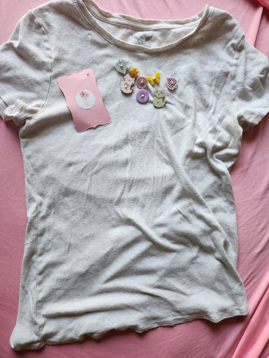 Cute t-shirt featuring quirky button designs in pastel colors for a playful fashion statement