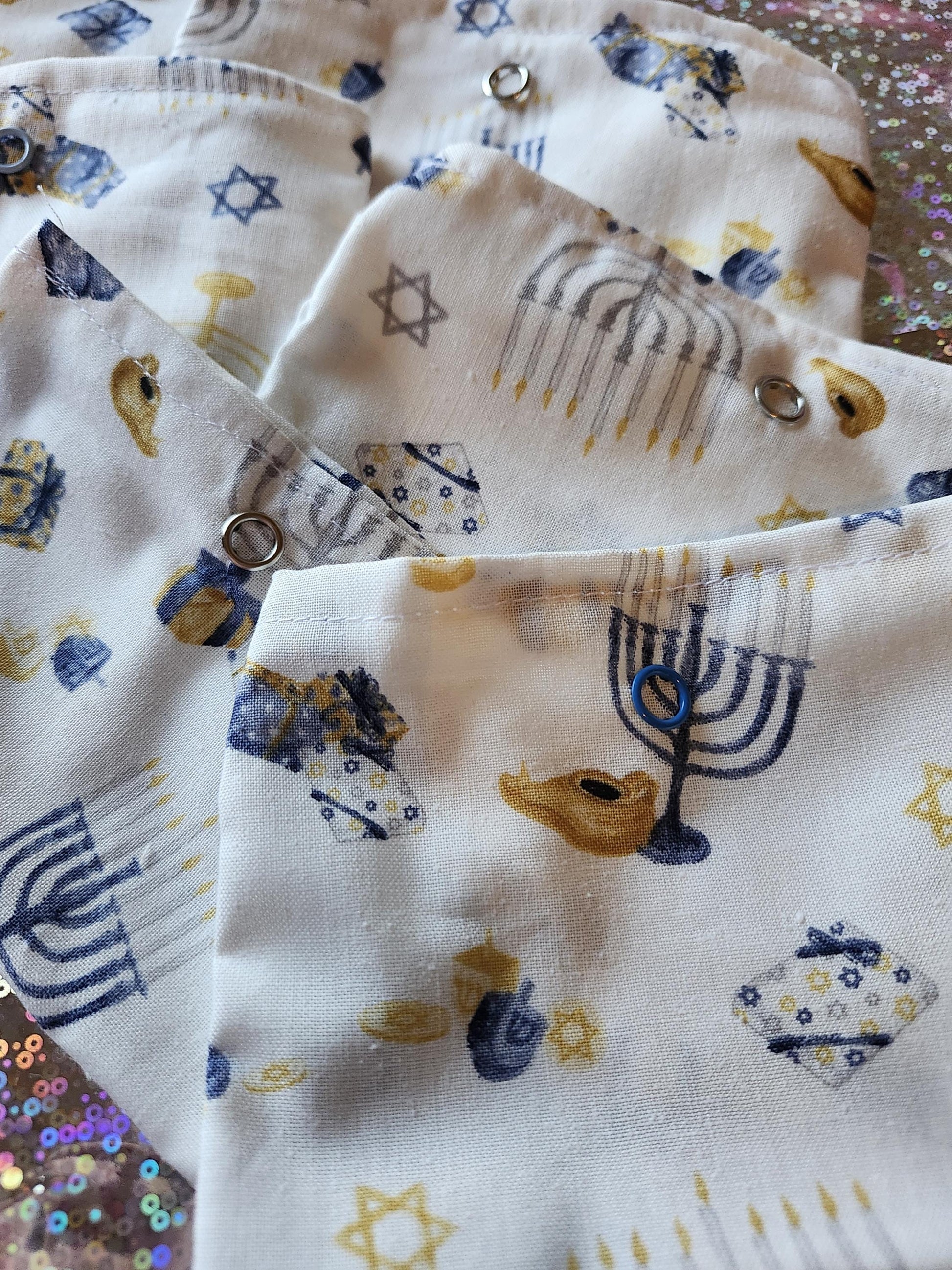 White Hanukkah gift pouch with colorful designs of menorahs and dreidels