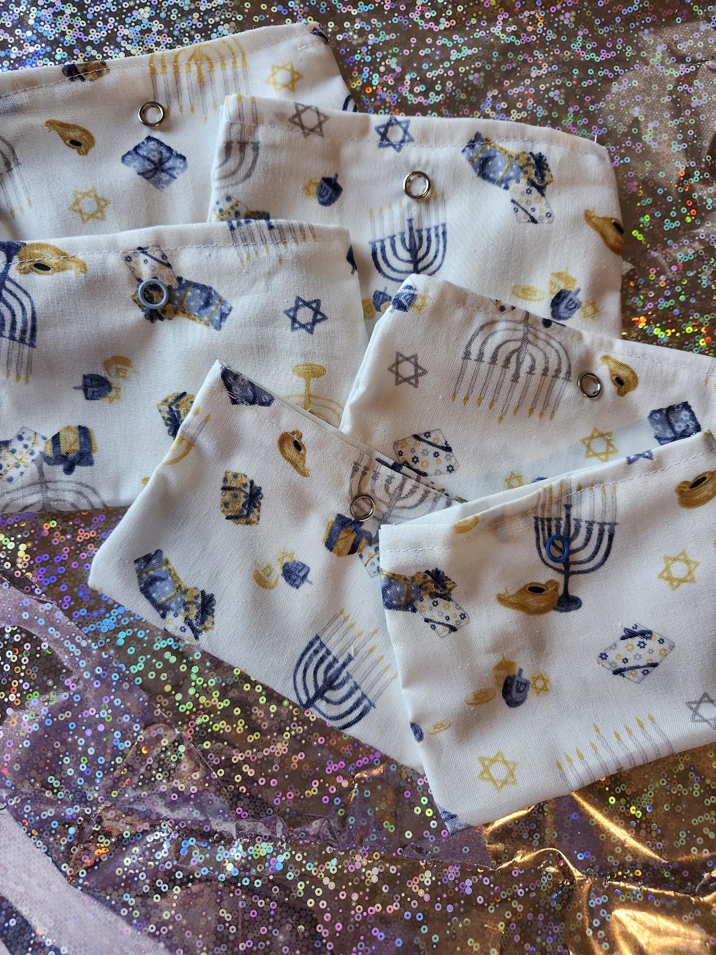 Set of White Hanukkah gift pouches featuring festive designs of menorahs and dreidels